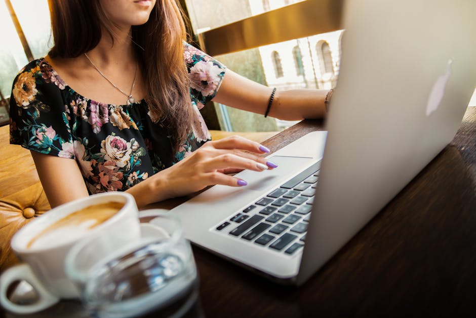 A woman working on a laptop in a cafe, sipping coffee, embodying a modern remote work lifestyle.
