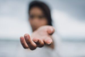 A soft focus image highlighting a reaching hand, symbolizing connection or help.