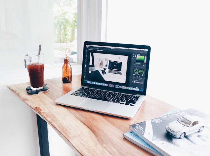 A cozy home office setup featuring a laptop and iced coffee on a wooden desk.