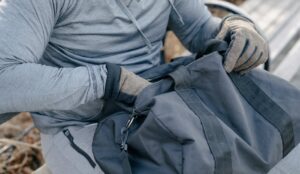 A person in activewear sits on a bench outdoors, holding a duffel bag, suggesting a fitness or casual outing.
